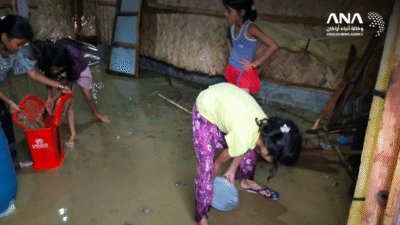 أطفال يحاولون إزاحة المياه التي غمرت مسكنهم جراء انهيار الخزان (صورة: ANA)